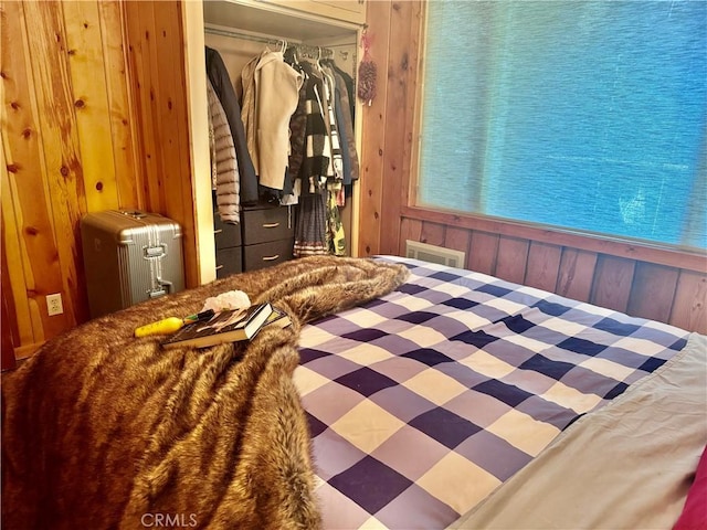 bedroom with wood walls, visible vents, and a closet