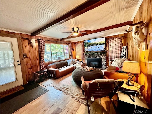 living room with a ceiling fan, a fireplace, wooden walls, beam ceiling, and wood-type flooring