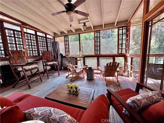 sunroom with beam ceiling, a wooden deck, and wood finished floors