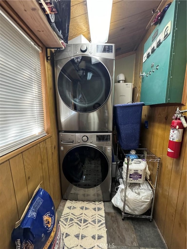 laundry room with stacked washer / dryer and wooden walls