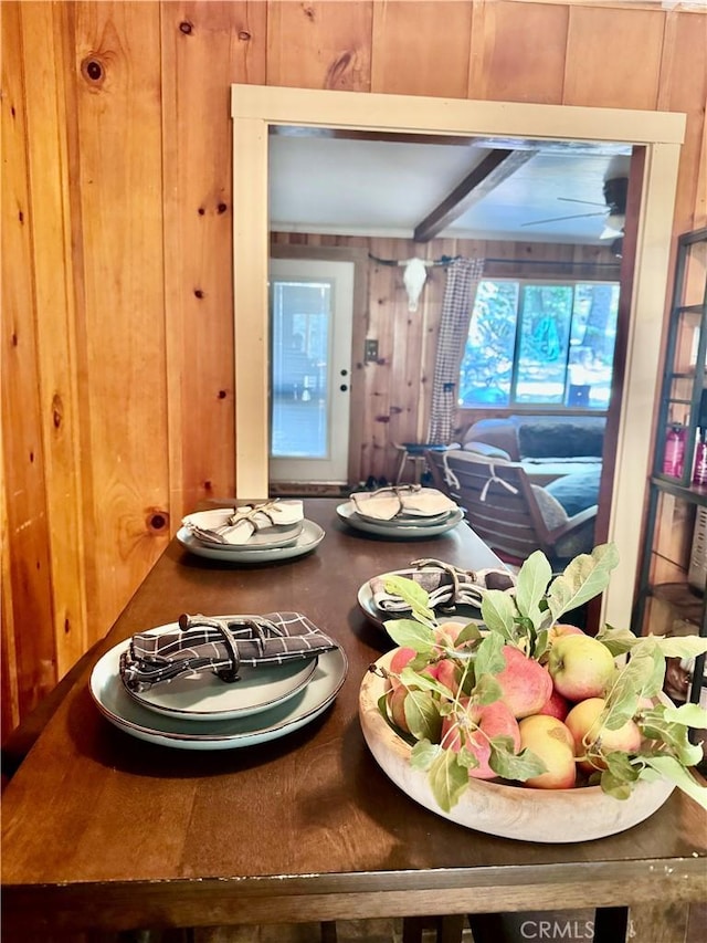 dining area featuring wooden walls and beamed ceiling