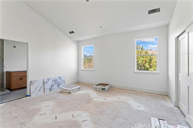 interior space with visible vents, baseboards, and vaulted ceiling