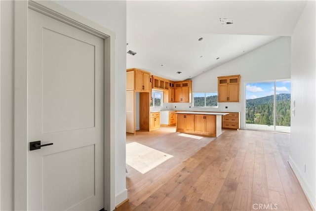 26701 Merced Ln, Lake Arrowhead, CA 92352 - kitchen featuring light wood-style flooring, light countertops, baseboards, a center island, and high vaulted ceiling