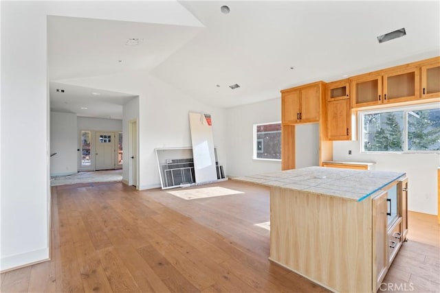 kitchen featuring tile counters, light wood-style floors, and lofted ceiling