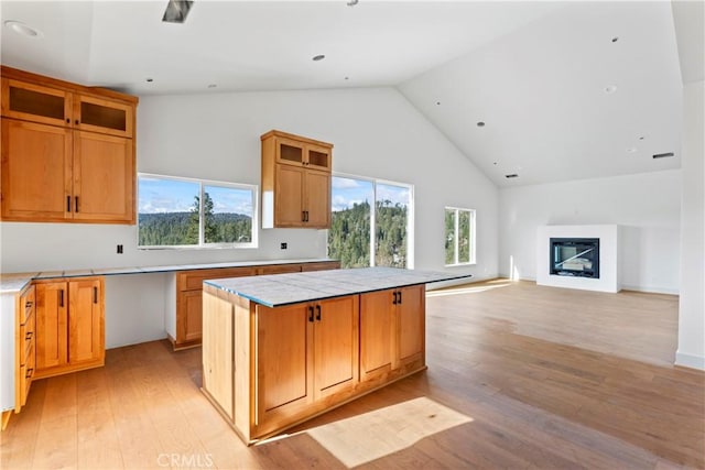 kitchen with high vaulted ceiling, a wealth of natural light, light wood-type flooring, and a kitchen island