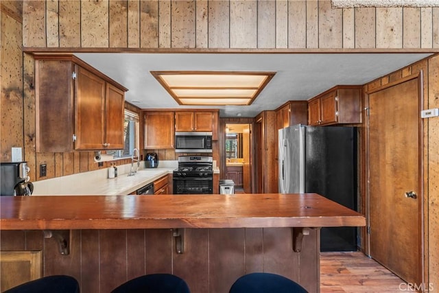 26375 Augusta Dr, Lake Arrowhead, CA 92352 - kitchen featuring a sink, light wood-type flooring, a peninsula, brown cabinetry, and stainless steel appliances