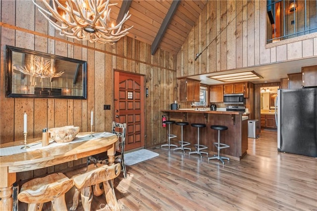 26375 Augusta Dr, Lake Arrowhead, CA 92352 - dining room featuring a chandelier, wood walls, light wood-style floors, and beamed ceiling