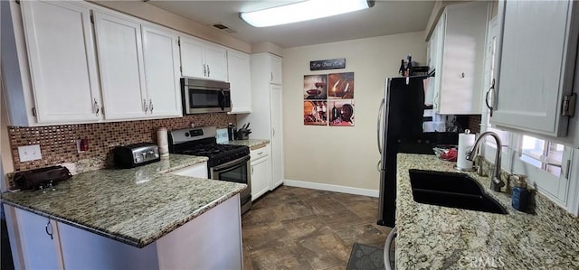 kitchen with white cabinets, tasteful backsplash, a sink, and appliances with stainless steel finishes