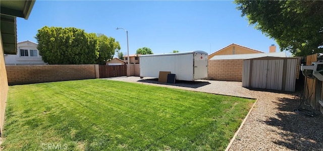 view of yard with a storage shed, a fenced backyard, and an outdoor structure