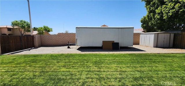view of yard featuring a storage shed, a fenced backyard, and an outdoor structure