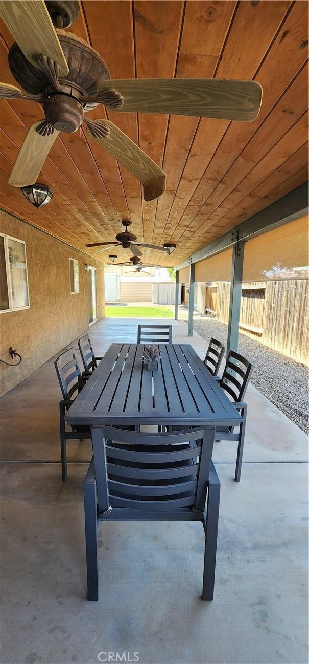 view of patio with ceiling fan, fence, and outdoor dining area