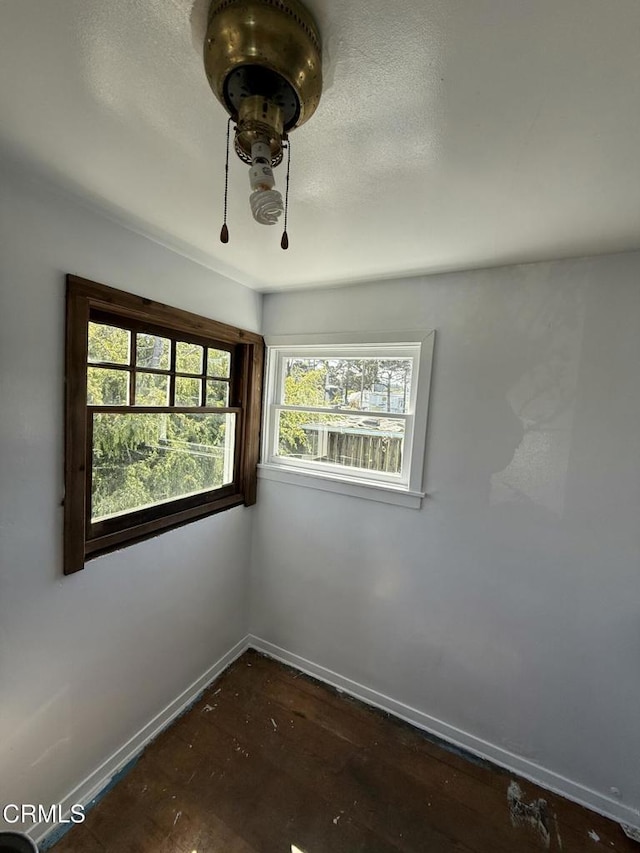 unfurnished room featuring baseboards and dark wood finished floors