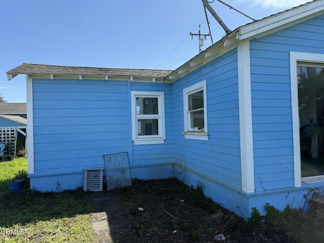 view of side of home with roof with shingles