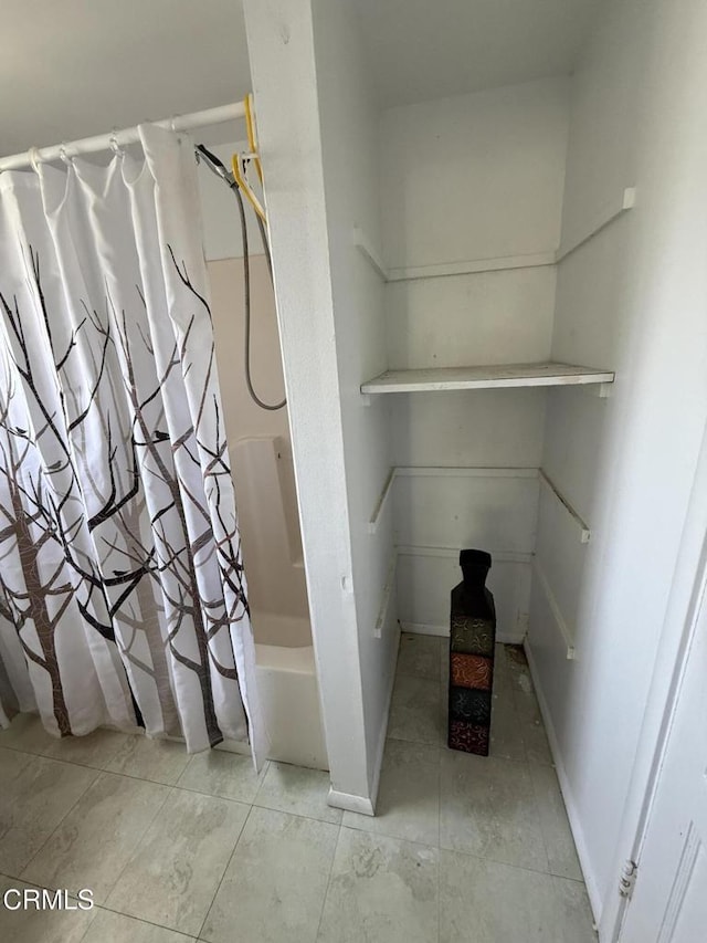 bathroom featuring baseboards, tile patterned flooring, and shower / tub combo with curtain