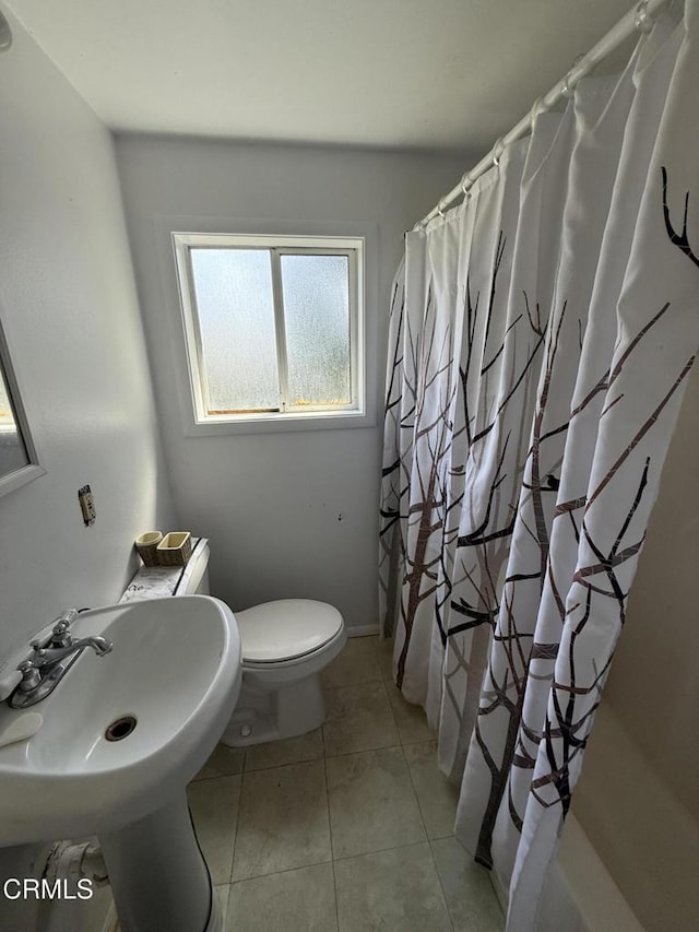 bathroom with a sink, a shower with shower curtain, tile patterned floors, and toilet