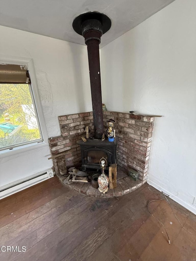 room details with baseboard heating, wood finished floors, and a wood stove