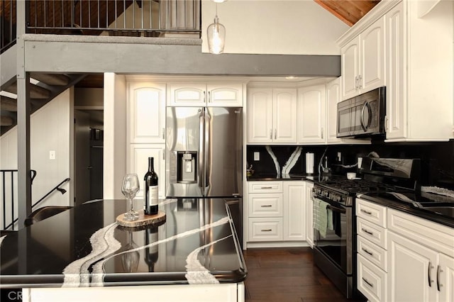 27482 Matterhorn Dr, Lake Arrowhead, CA 92352 - kitchen with gas range, black microwave, dark countertops, stainless steel fridge with ice dispenser, and dark wood-style flooring