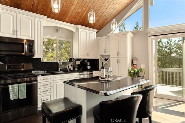 27482 Matterhorn Dr, Lake Arrowhead, CA 92352 - kitchen featuring appliances with stainless steel finishes, dark countertops, tasteful backsplash, white cabinetry, and a kitchen bar