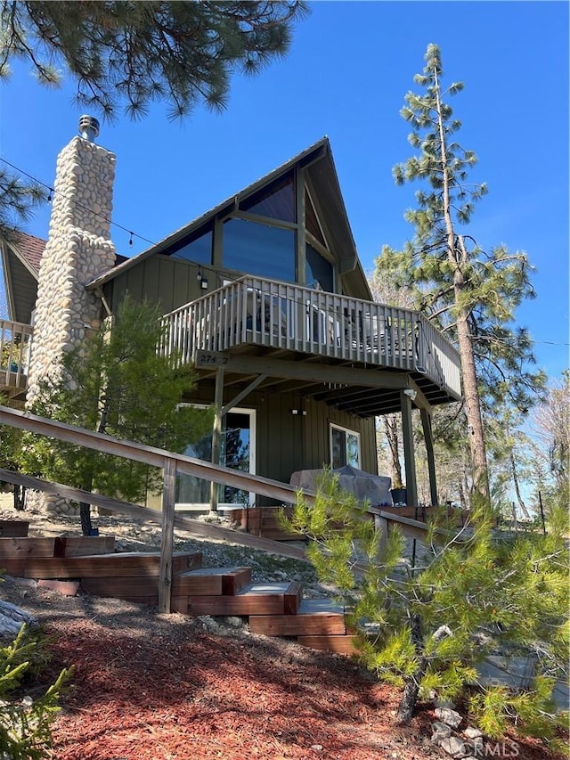 27482 Matterhorn Dr, Lake Arrowhead, CA 92352 - rear view of house with board and batten siding, a wooden deck, and a chimney