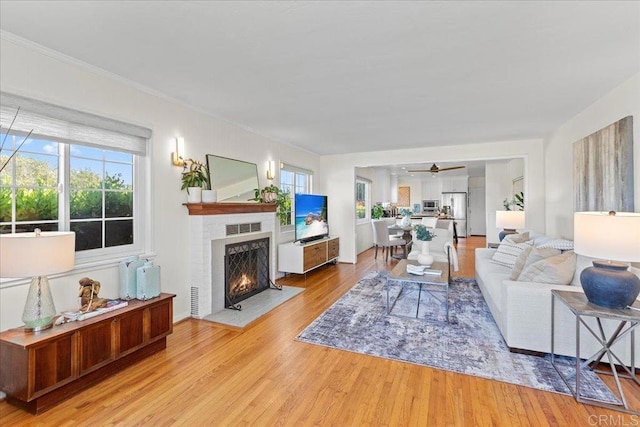 1045 Tarento Dr, San Diego, CA 92107 - living room with light wood-type flooring, plenty of natural light, a lit fireplace, ceiling fan, and crown molding