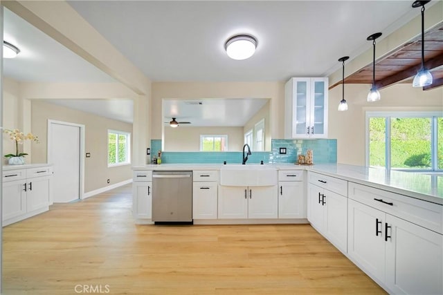 kitchen featuring tasteful backsplash, a sink, dishwasher, light wood-type flooring, and glass insert cabinets
