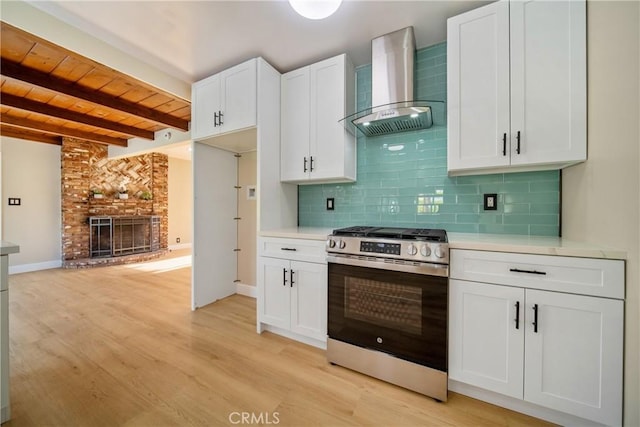 kitchen with wall chimney range hood, stainless steel gas range, light wood finished floors, light countertops, and wooden ceiling