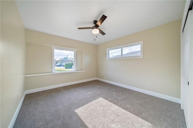 carpeted empty room featuring a ceiling fan and baseboards