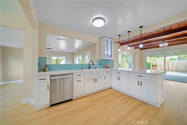 kitchen with a sink, light wood finished floors, a peninsula, and dishwasher