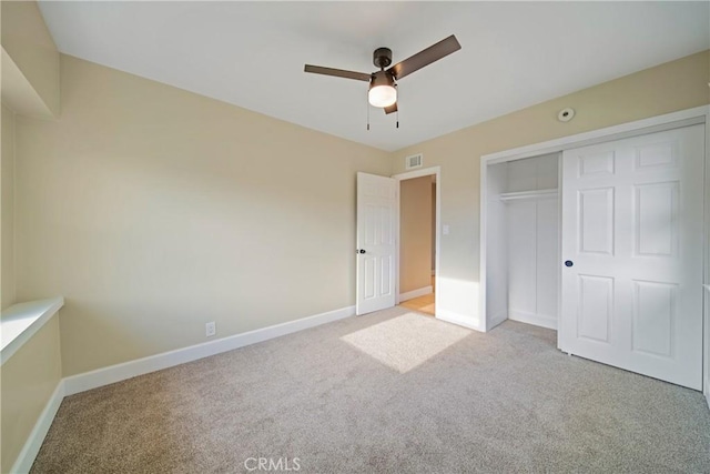 unfurnished bedroom with ceiling fan, visible vents, light colored carpet, baseboards, and a closet