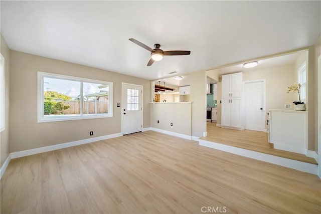 unfurnished living room with ceiling fan, baseboards, and light wood-type flooring