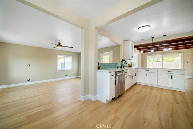 kitchen featuring stainless steel dishwasher, light countertops, light wood-style floors, and a peninsula