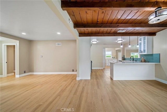 unfurnished living room with light wood-style floors, baseboards, wooden ceiling, beamed ceiling, and visible vents