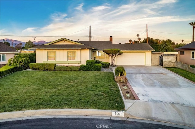 ranch-style home with fence, a garage, driveway, and a front lawn