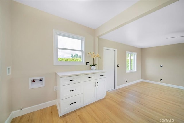 washroom with washer hookup, baseboards, light wood-type flooring, and cabinet space