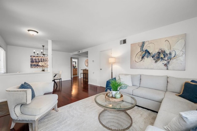 living area featuring visible vents, wood finished floors, and a notable chandelier