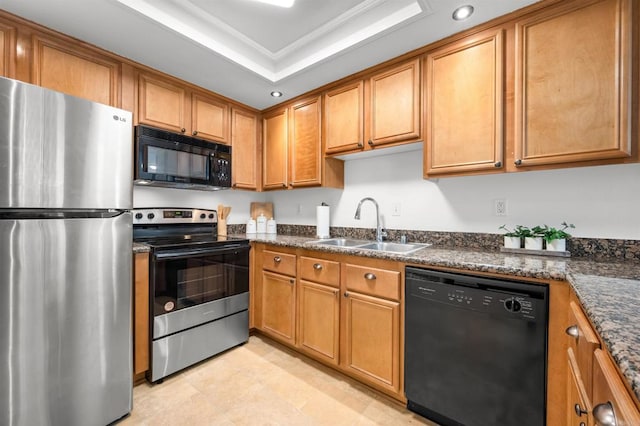 kitchen with brown cabinets, recessed lighting, a tray ceiling, a sink, and black appliances