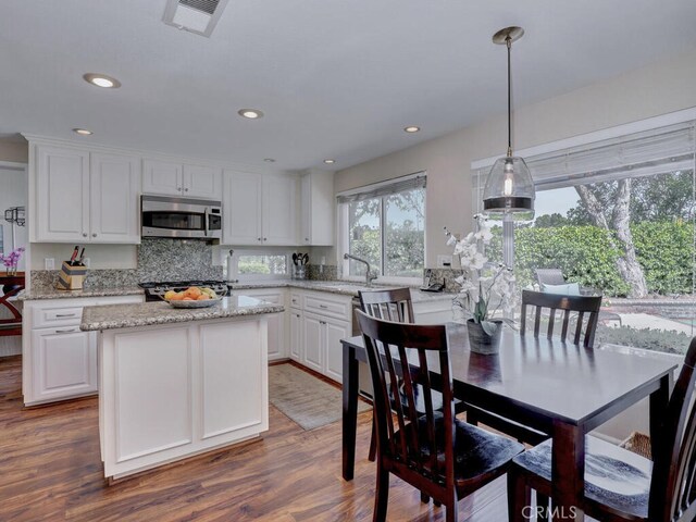 27275 Comba, Mission Viejo, CA 92692 - kitchen with stainless steel microwave, white cabinets, wood finished floors, decorative light fixtures, and recessed lighting