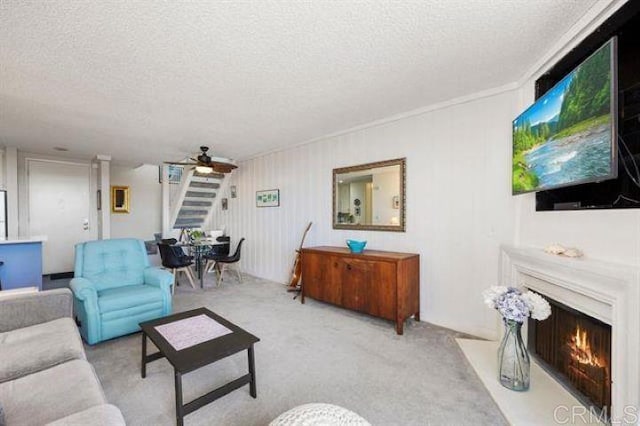 999 N Pacific St Unit G326, Oceanside, CA 92054 - carpeted living area featuring a textured ceiling, a ceiling fan, a lit fireplace, and stairs