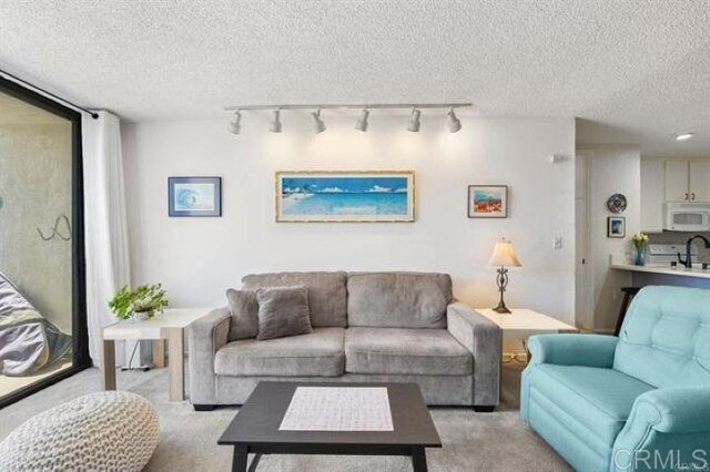 999 N Pacific St Unit G326, Oceanside, CA 92054 - living area featuring a textured ceiling, light carpet, and track lighting