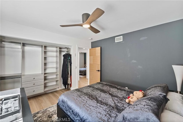 bedroom featuring ceiling fan, visible vents, a closet, and wood finished floors