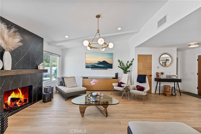 living room with a notable chandelier, recessed lighting, visible vents, a high end fireplace, and wood finished floors