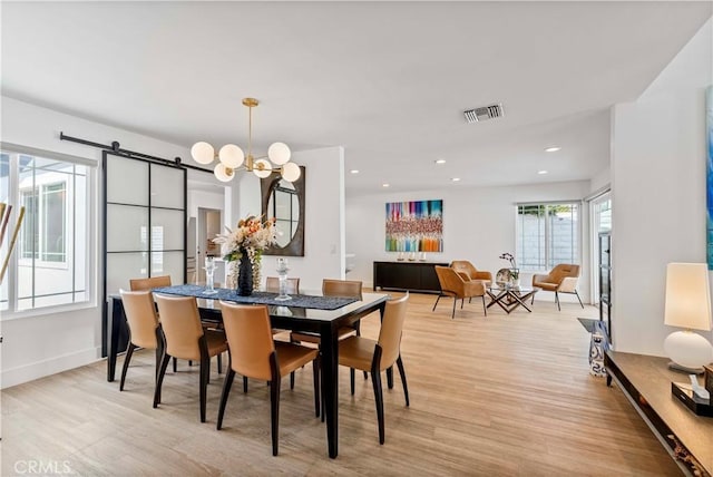dining room with visible vents, a barn door, a notable chandelier, light wood-style floors, and recessed lighting