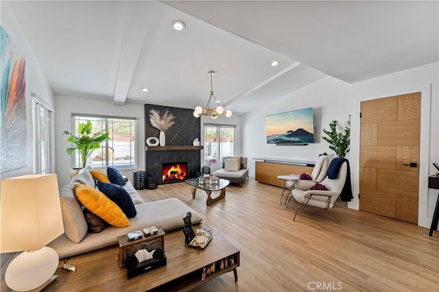living room featuring light wood-style flooring, a premium fireplace, a notable chandelier, and recessed lighting