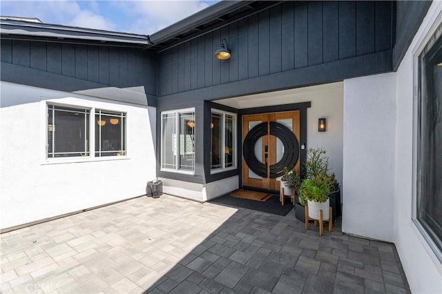 view of exterior entry with a patio and stucco siding