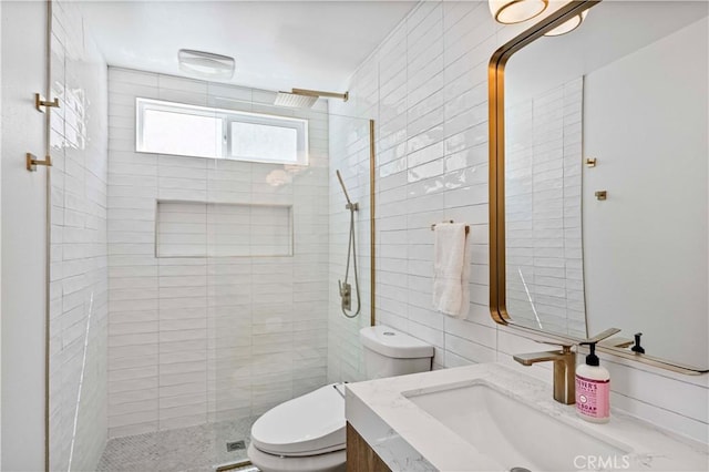 bathroom featuring tiled shower, vanity, tile walls, and toilet