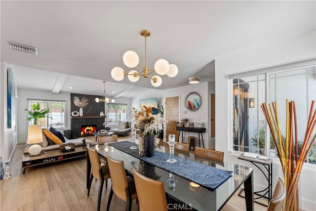 dining space featuring a notable chandelier, baseboards, a fireplace, visible vents, and wood finished floors