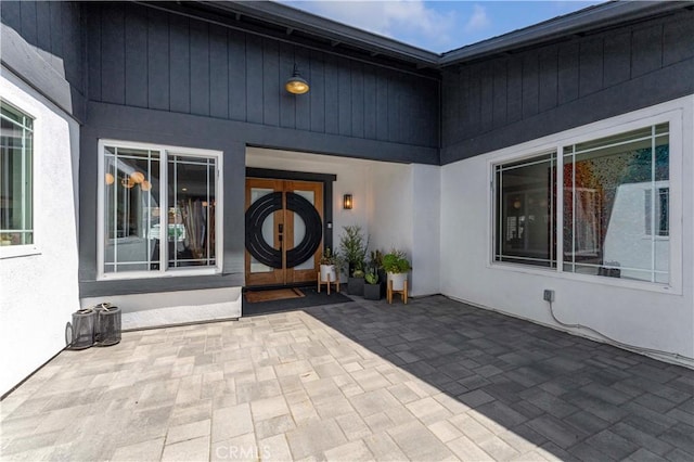 entrance to property with a patio area, french doors, and stucco siding
