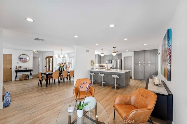 living room with recessed lighting, a notable chandelier, visible vents, and light wood-style flooring