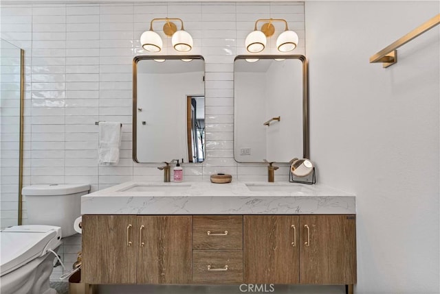 bathroom with a sink, tile walls, toilet, and double vanity