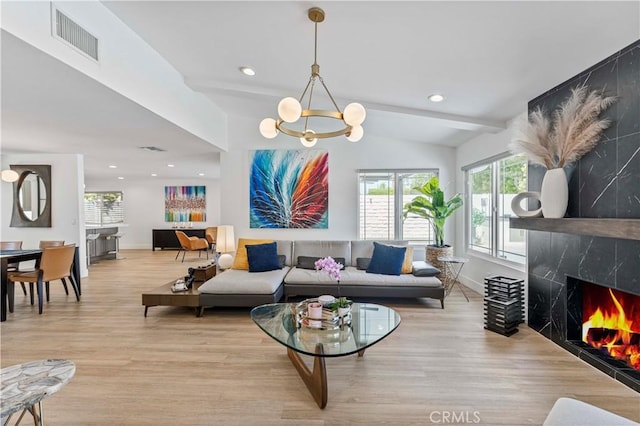 living area with visible vents, baseboards, an inviting chandelier, light wood-type flooring, and vaulted ceiling